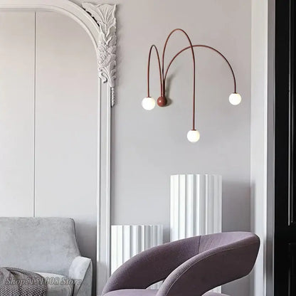 A modern wall lamp with three curved copper-toned decorbites branch glass iron arms and white spherical bulbs