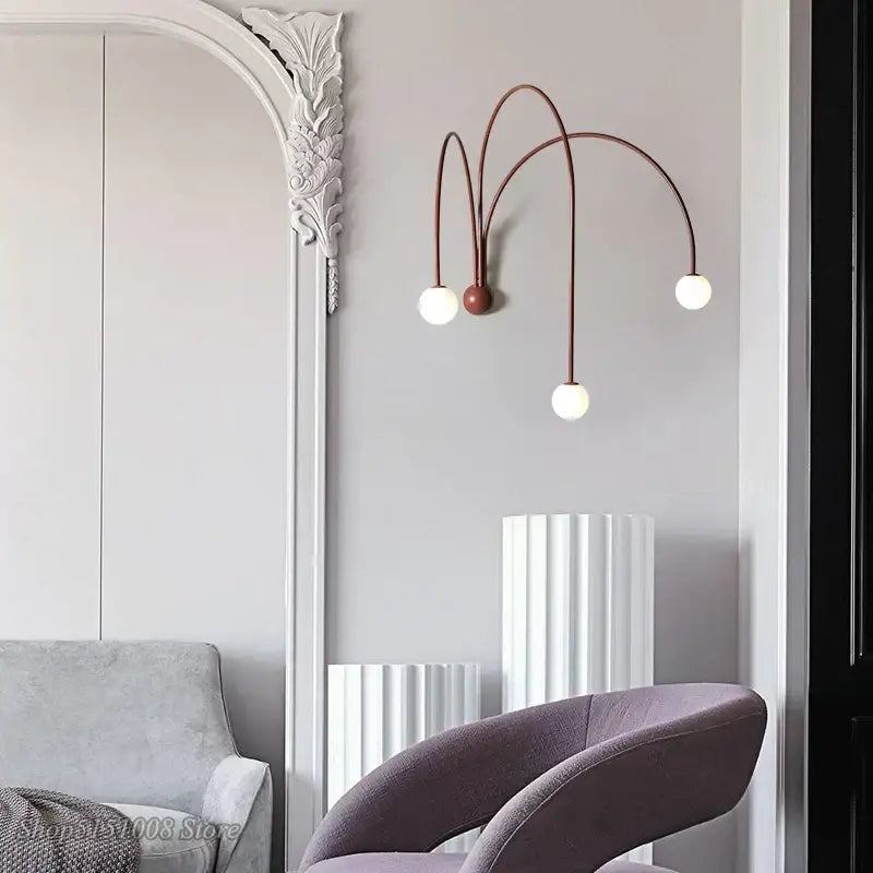 A modern wall lamp with three curved copper-toned decorbites branch glass iron arms and white spherical bulbs