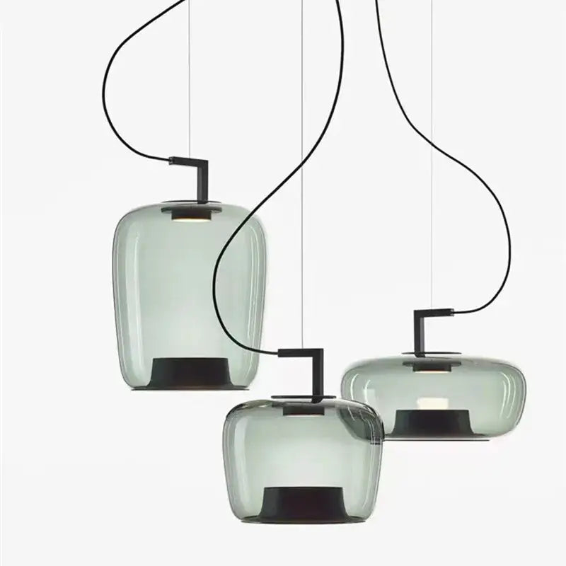 Three modern pendant lamps with translucent sage green glass pendant shades and black metal fixtures for dining room use
