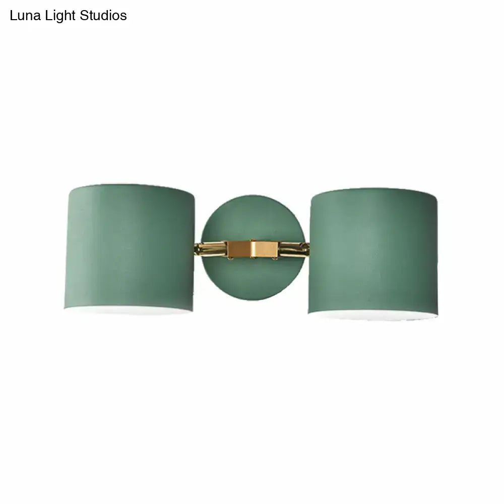 Modern sage green double shade wall sconce with matte cylindrical shades and brass bracket, 12 inches high for living room lighting
