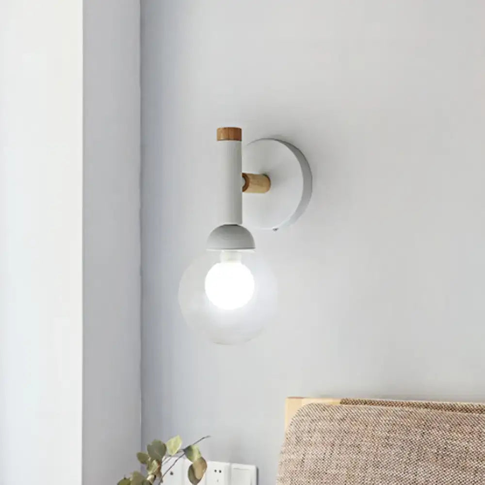 Minimalist wall light with matte white cylindrical body, wooden accents, and clear glass globe in macaron style torch design