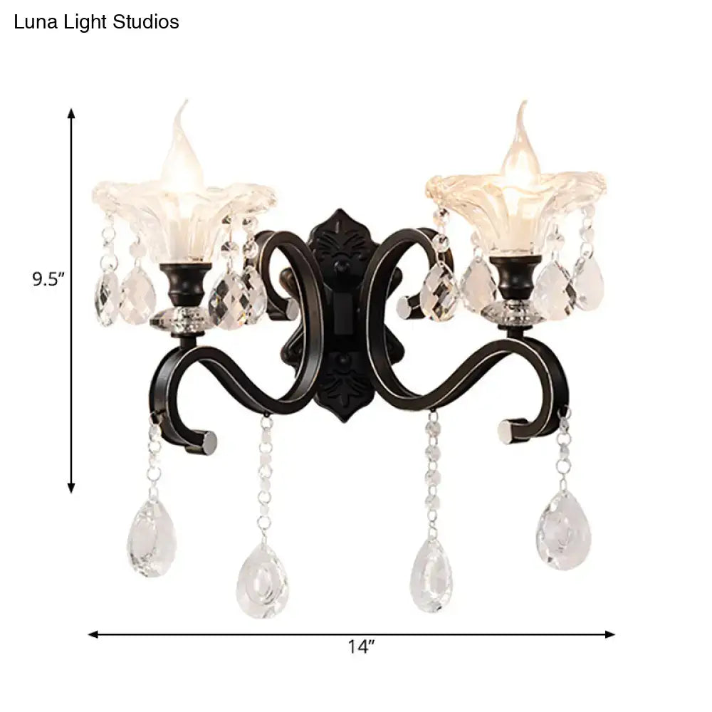 Modern scalloped black wrought iron wall lamp with curved arm, two candle glass shades, direct wired with crystal pendants