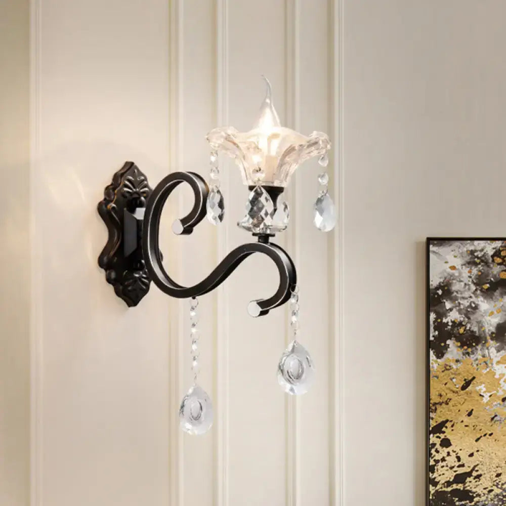 Elegant black wrought iron wall lamp with curved arm direct wired featuring clear crystal droplets and faceted glass shade
