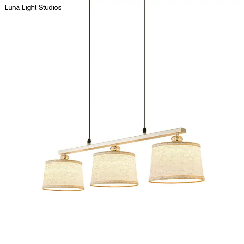 DecorBites modern three-light pendant light with white wooden bar brass accents and flaxen fabric shades for kitchen island