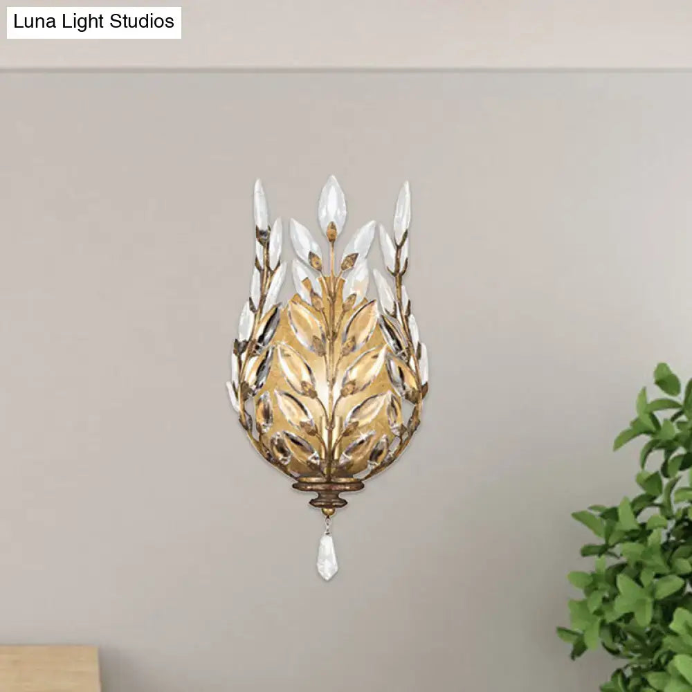 Gold-toned wall light with silver brass laurel design and crystal drop accents for bedroom lighting