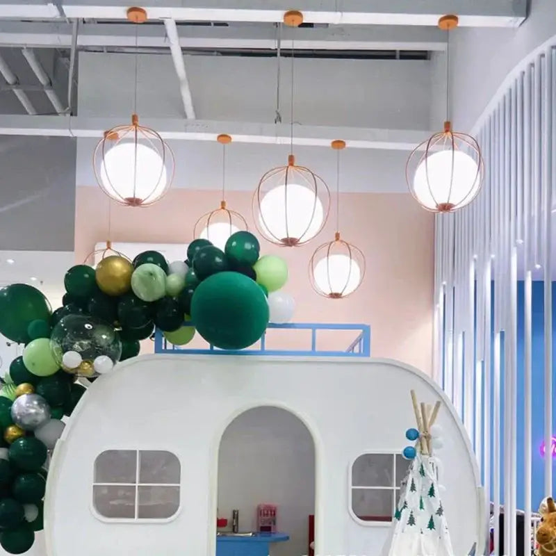 White camper-style playhouse featuring an arched doorway and rectangular windows complementing decorbites birdcage pendant light