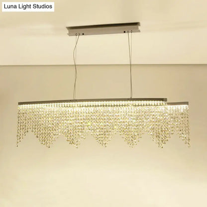 A modern silver crystal island pendant chandelier with a sleek metallic frame and clear crystal beads for dining room