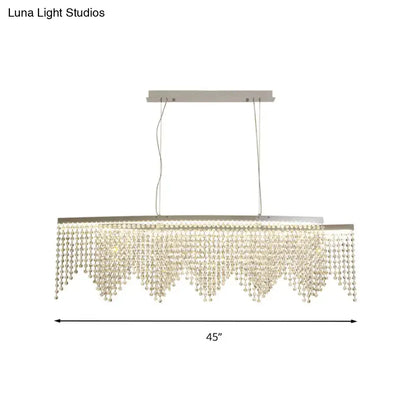 A modern silver crystal island pendant chandelier with a sleek metal frame and clear faceted beads for dining rooms