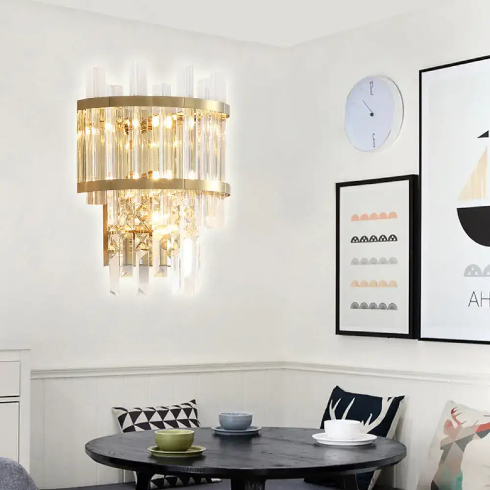 Modern gold-toned wall mounted wall light with cascading clear crystal prisms and fixture width suited for dining rooms