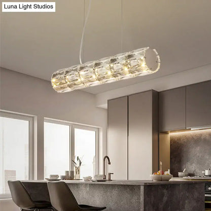 Modern silver crystal tube island light with cylindrical segmented faceted design refracting warm ambient lighting