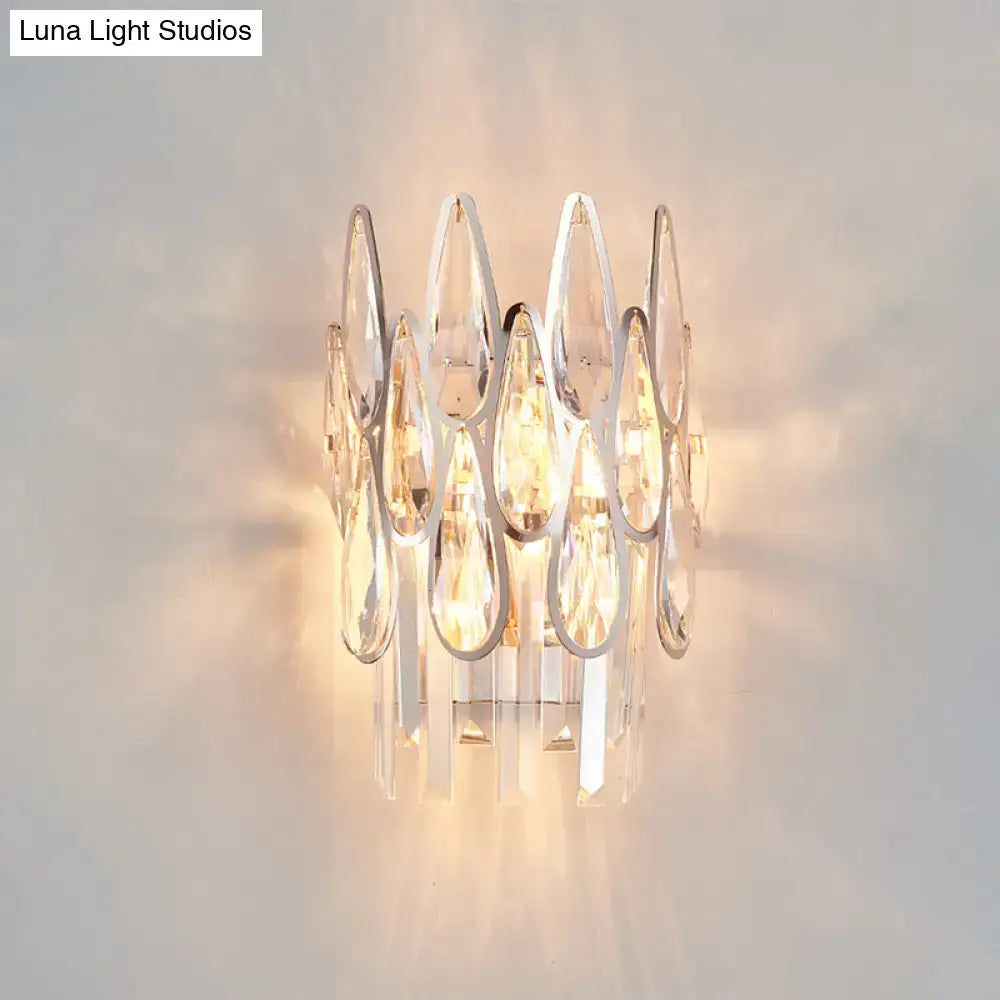 Modern silver crystal wall sconce featuring clear teardrop crystals and sleek chrome accents for living room lighting
