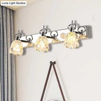Modern silver finish wall light with clear glass crystal flower shades emitting warm glow for bathroom vanity