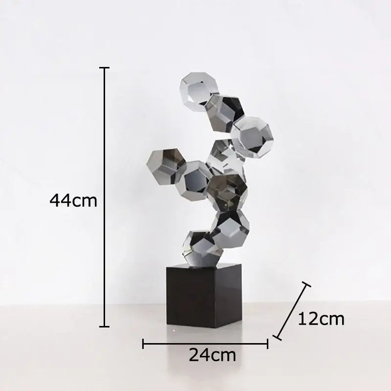 A modern silver geometric crystal ball desk ornament with interlocking faceted spheres on a black base