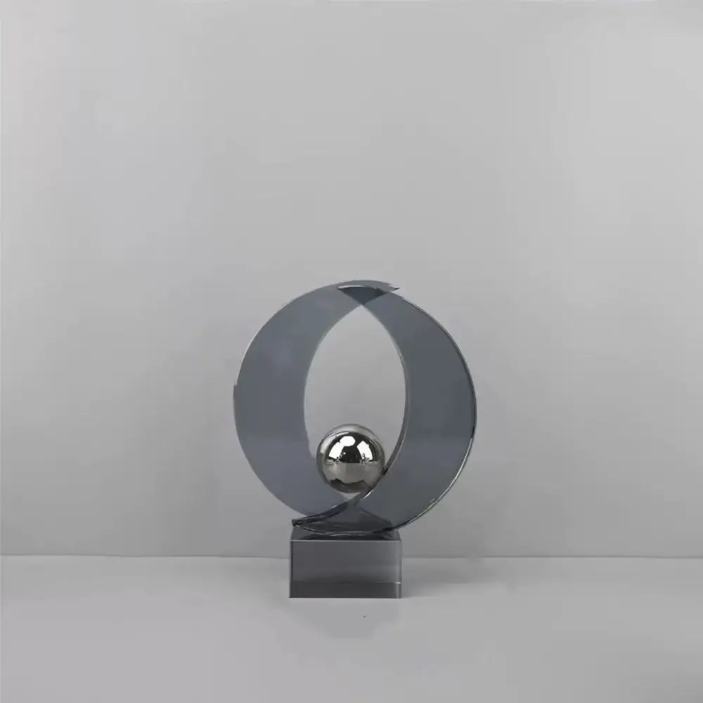 Modern silver geometric crystal sculpture featuring a sleek curved ring with a reflective sphere for home decor