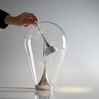 A modern silver decorbites glass desk lamp with a transparent dome and metallic base ideal for bedroom lighting