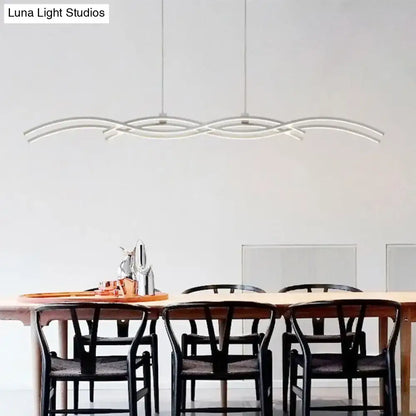 Modern silver wave island pendant light with acrylic curved arms suspended above a dining table by DecorBites