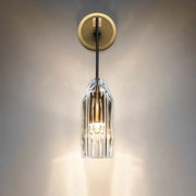 Modern single light brass wall sconce with clear crystal faceted shade and brass accents for bedroom lighting