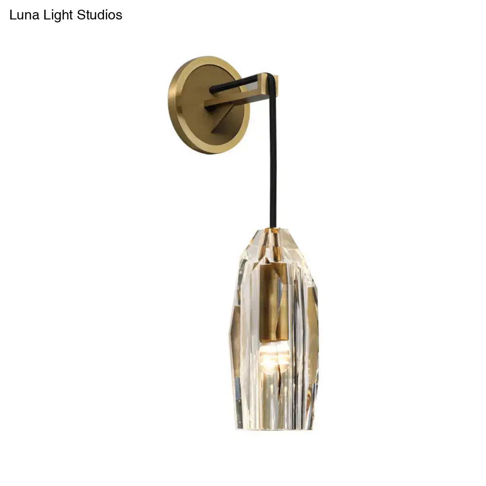 Modern single light brass wall sconce with clear crystal faceted shade and brass accents for bedroom lighting