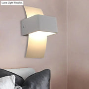 Modern sleek white wall sconce with a sleek angular design and warm ambient led light for bedroom use