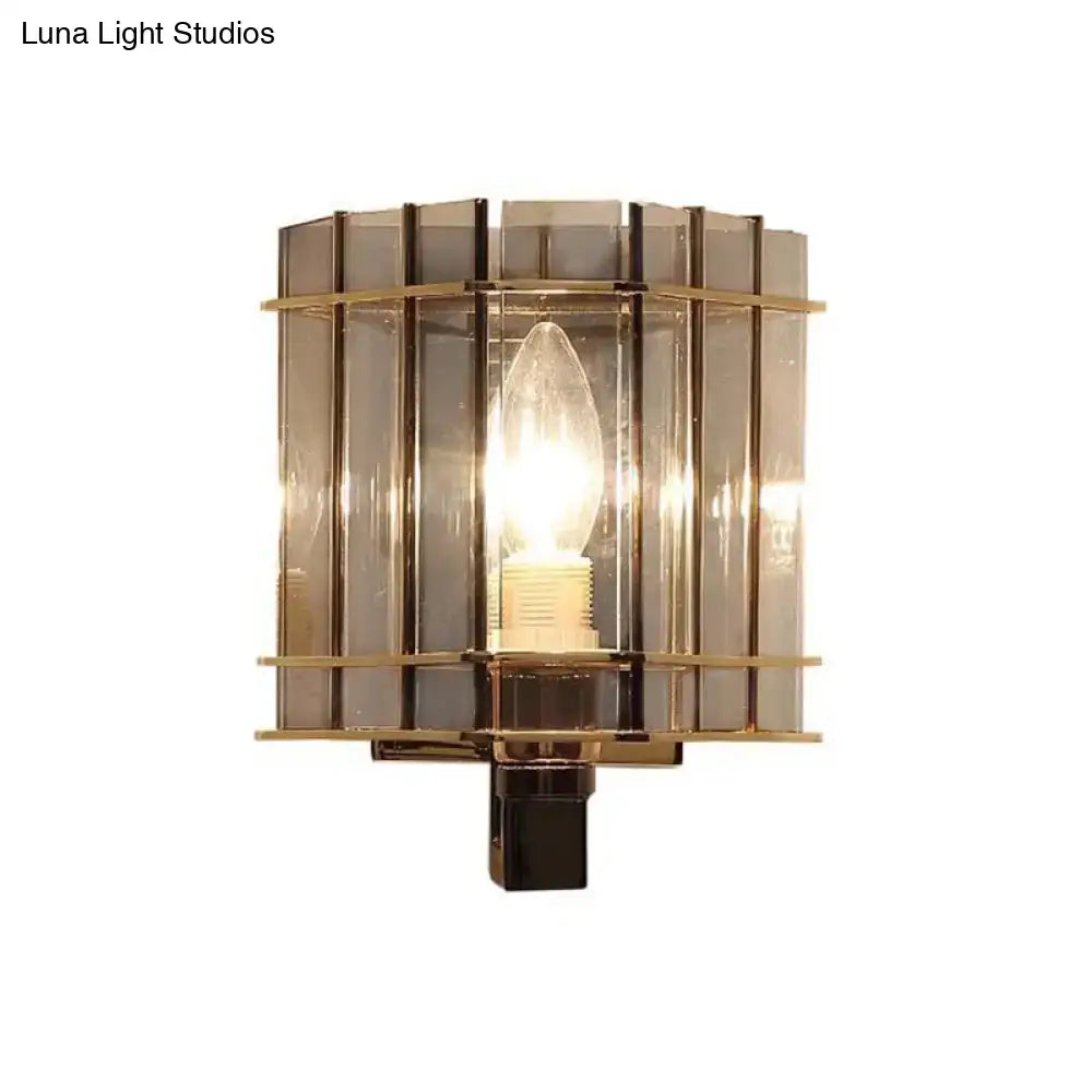 Brass-framed modern wall light with vertical smoke gray glass panels and central incandescent bulb for bedroom use