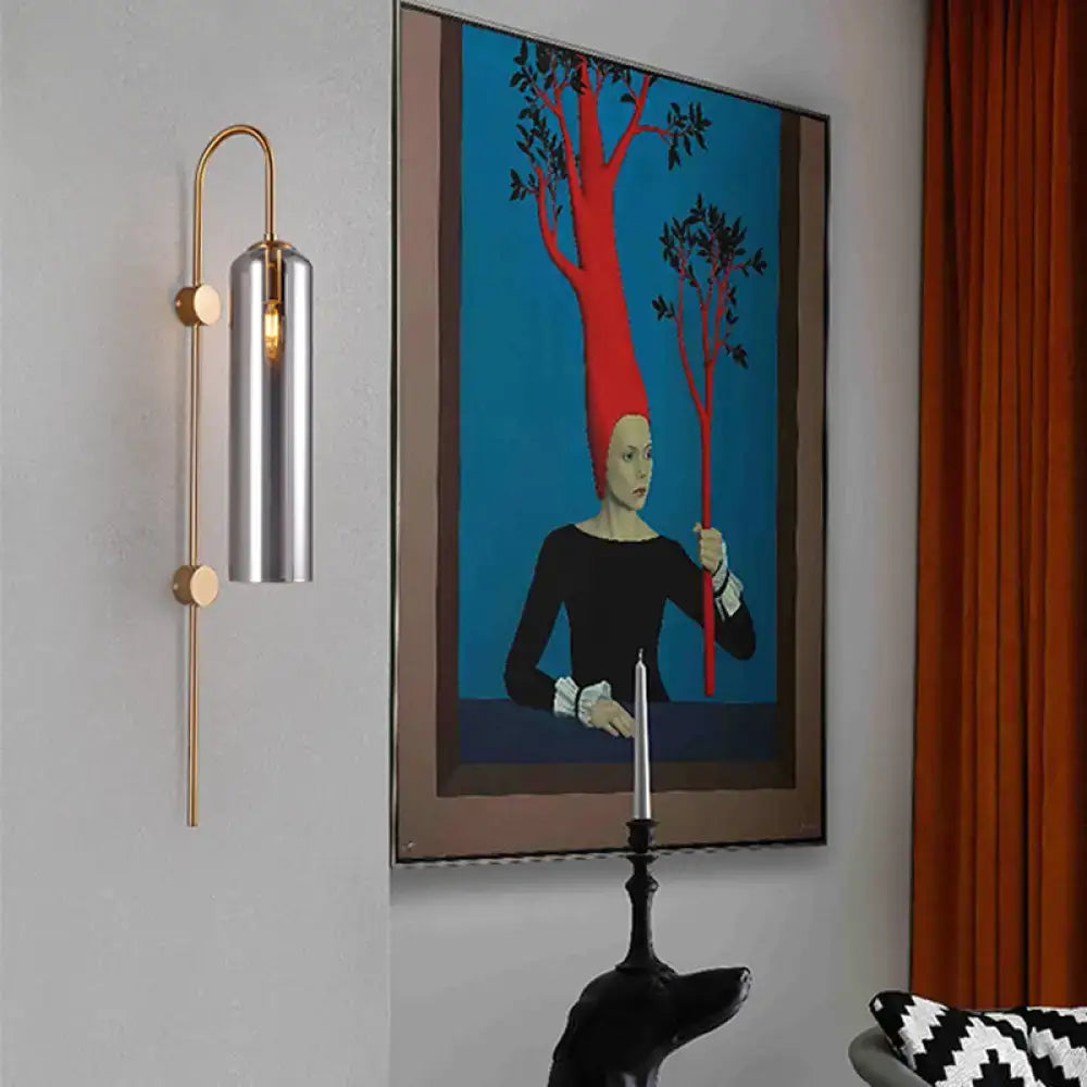 A modern smoke gray glass wall light with brushed silver cylindrical shade and gold-toned arms for living room use