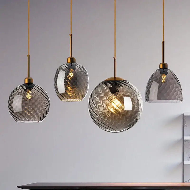 Set of four modern pendant lights with textured smoked glass shades and brass accents for kitchen use