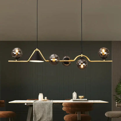 Modern gold-toned pendant light with a sleek curved frame and five smoky grey glass globe shades for dining rooms