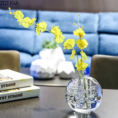 Modern spherical clear glass vase with bubbles by decorbites holding bright yellow orchids for desk decoration
