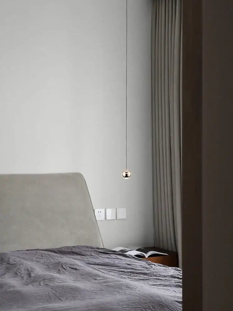 A minimalist spherical gold led pendant lamp with polished gold finish hanging from thin cord for dining room decorbites