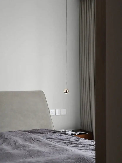 A minimalist spherical gold led pendant lamp with polished gold finish hanging from thin cord for dining room decorbites