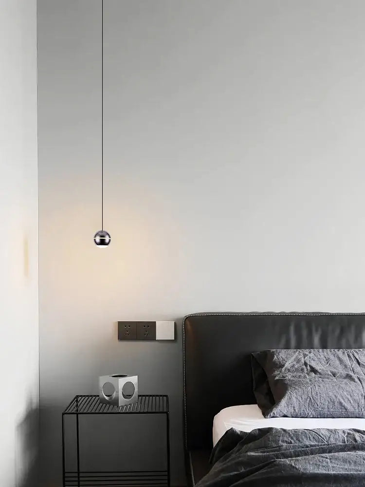 A modern spherical gold led pendant lamp with a polished metallic finish hanging from a black cord for dining room decorbites gold led lighting