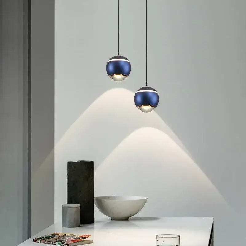 Two deep blue metallic spherical pendant lights with silver accents hang from thin cords in modern led bedside decorbites