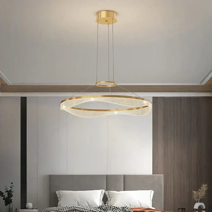 Modern spiral acrylic ring pendant light fixture with gold-toned woven mesh design and embedded LED lighting