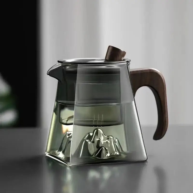 Modern square glass tea pot with wooden handle and lid knob featuring metal mountain-shaped infuser at the base