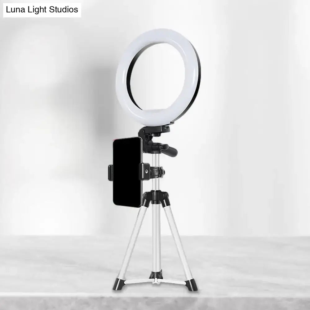 Modern style white led ring flash light with black phone clamp mounted on silver tripod for office use