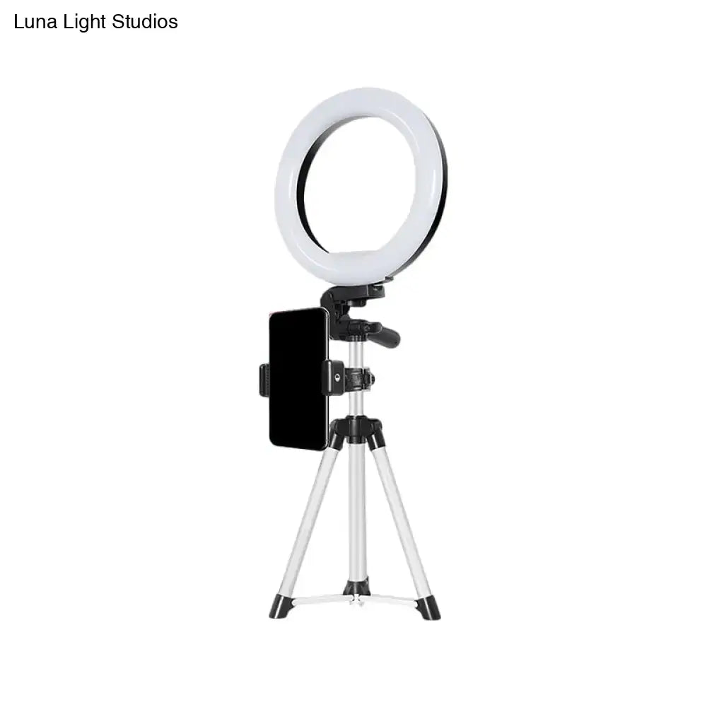 Modern style white led ring flash light with black phone clamp mounted on silver tripod for office use