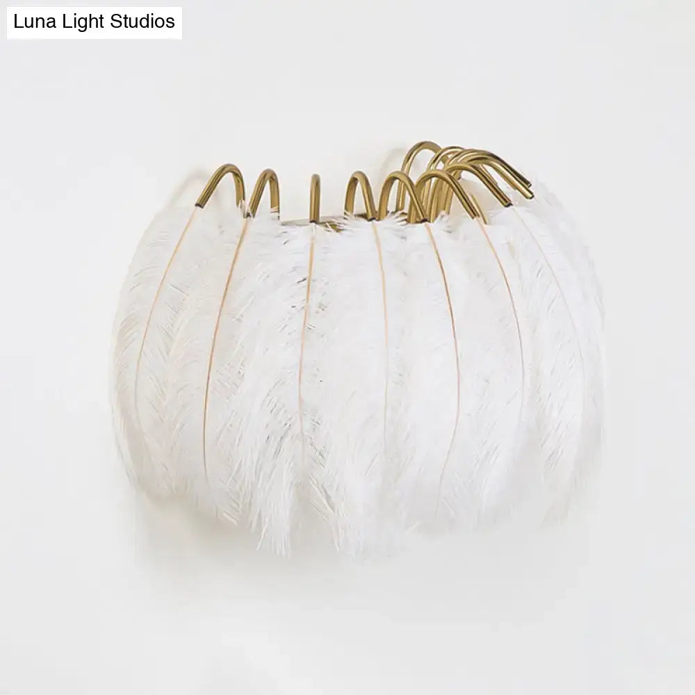 Modern style grey white sconce light featuring a white feathered pumpkin decoration with gold toned metal hooks