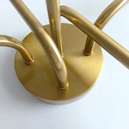 Gold-toned metal coat rack with circular base and curved arms complements modern decorbites brass ceiling light design