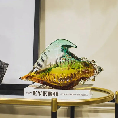Modern teal and amber glass conch shell statue featuring iridescent translucence and intricate ridged detailing for decor