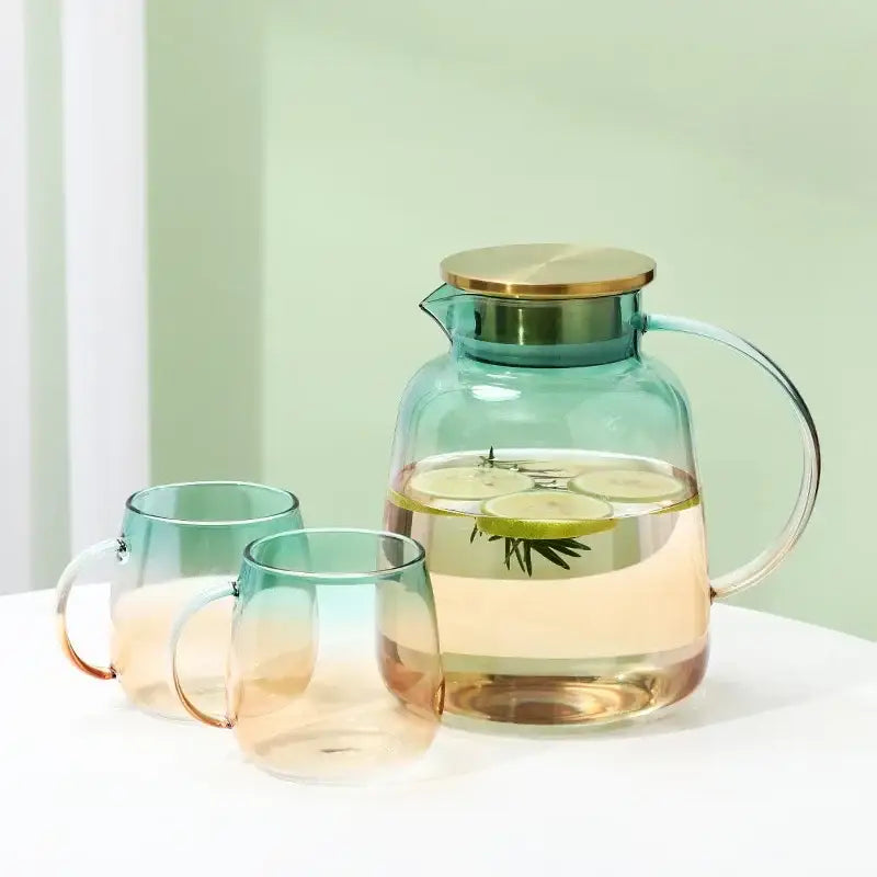 Modern teal and gold glass teapot set featuring a transparent glass pitcher with gold lid filled with infused water