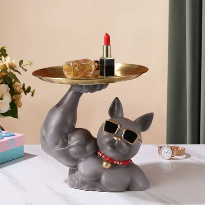Gray ceramic decorbites bulldog tray with muscular arms wearing gold-rimmed sunglasses and red beaded collar holding golden tray