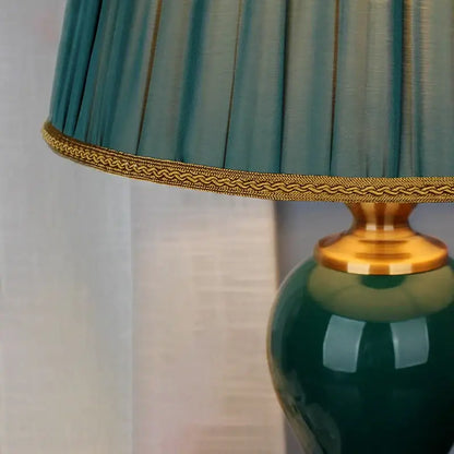Modern teal green ceramic table lamp with pleated lampshade and gold trim for bedroom and living room use
