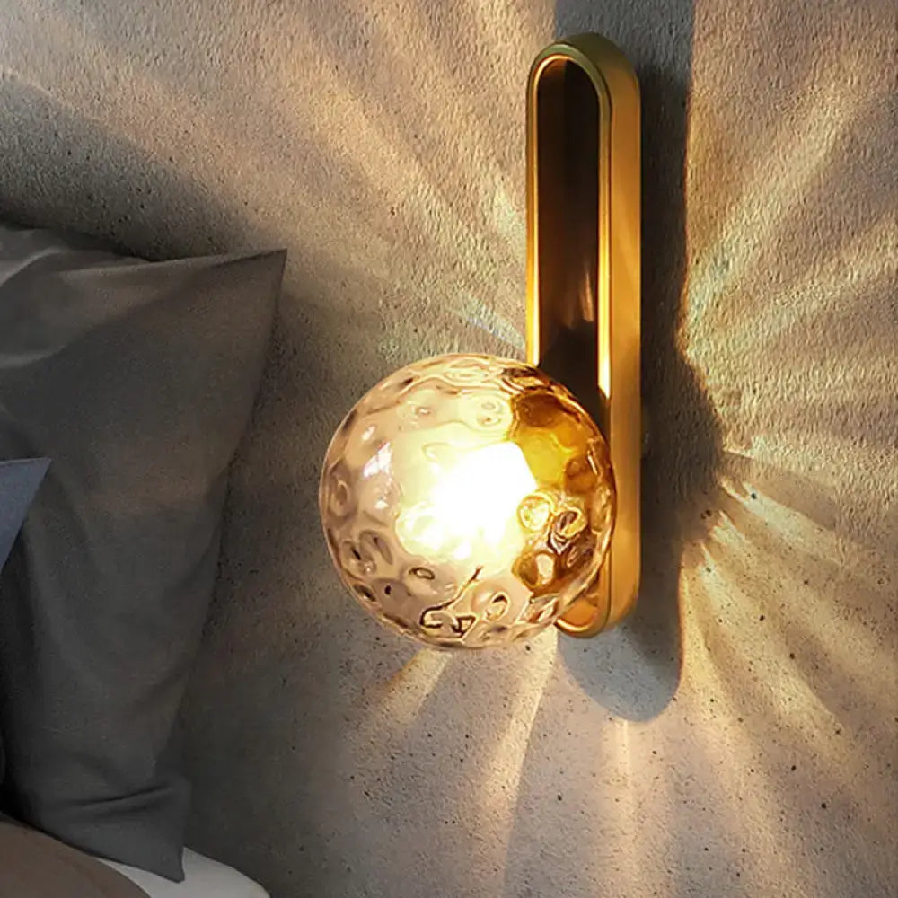 Modern teal and terracotta side table with a gold-toned orb wall light featuring textured amber glass globe
