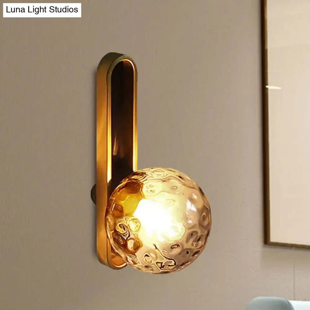 Modern teal and terracotta cylindrical side table with a gold-toned orb wall light featuring textured amber glass globe