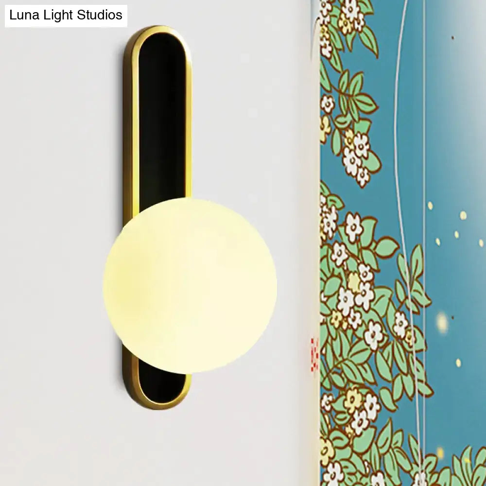 Modern teal and terracotta cylindrical side table paired with a gold metal orb wall light featuring a frosted glass shade