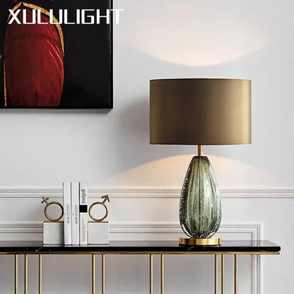 A sleek teardrop textured green and gold glass table lamp on a modern console table for bedroom decorbites use
