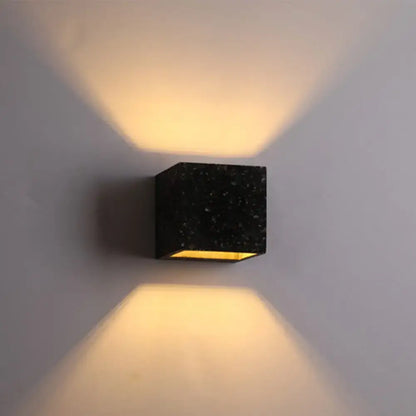 Modern terrazzo black speckled stone cube wall light with warm yellow e26 e27 light bulb casting angled beams