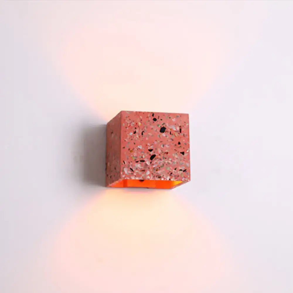 A coral-colored terrazzo cube wall light with glowing orange interior compatible with e26 e27 light bulbs