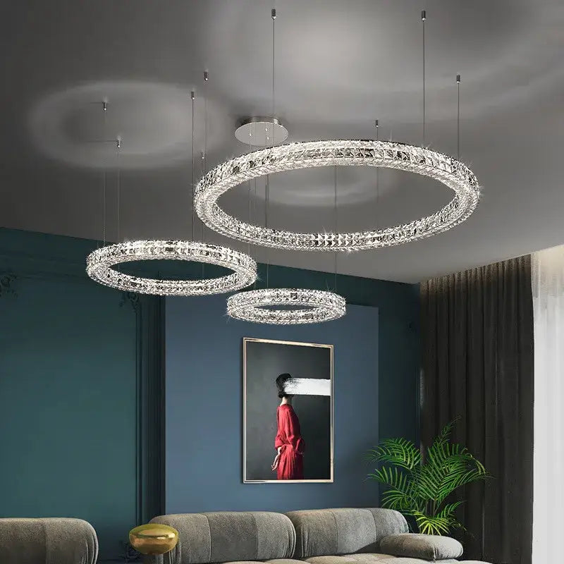 Three elegant crystal encrusted circular decorbites crystal led chandeliers hang from the ceiling in a modern living room