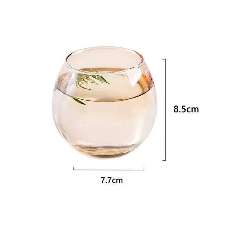 A modern transparent glass coffee mug with a clear rounded amber-tinted glass tumbler for kitchen and dining room
